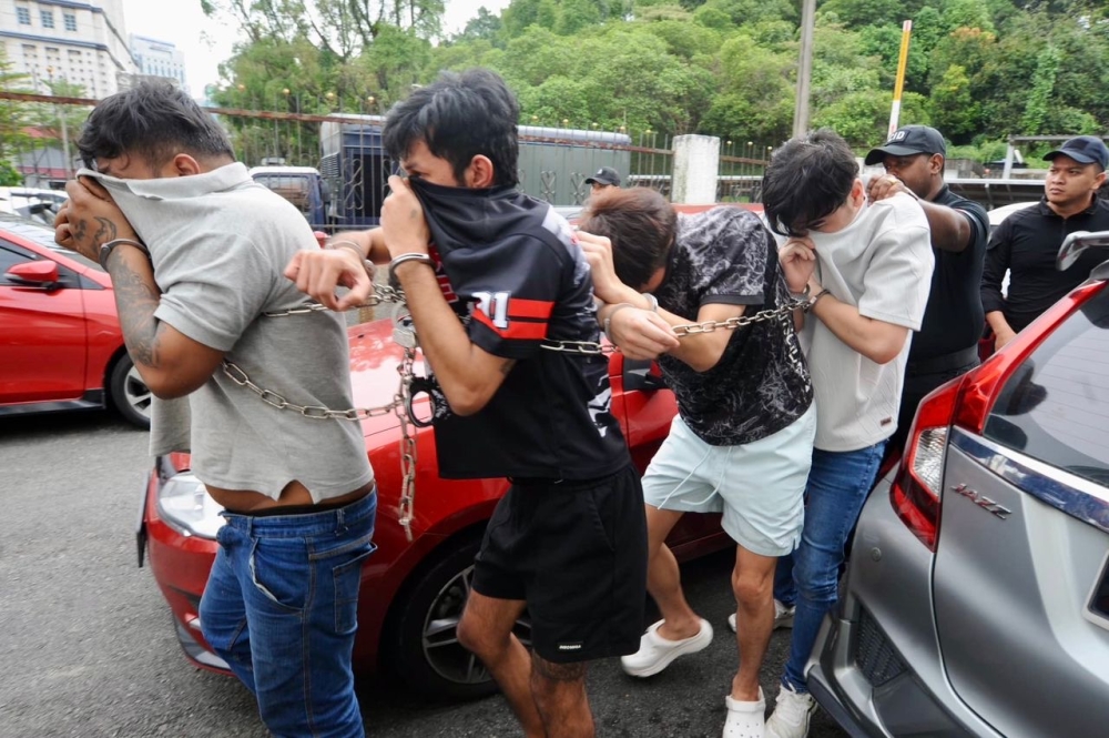 The group of six youths, who are part of an alleged online fraud and sexual extortion syndicate, being led into the Johor Baru Court Complex today where they were charged for multiple offences. July 15, 2025. — Picture by Ben Tan