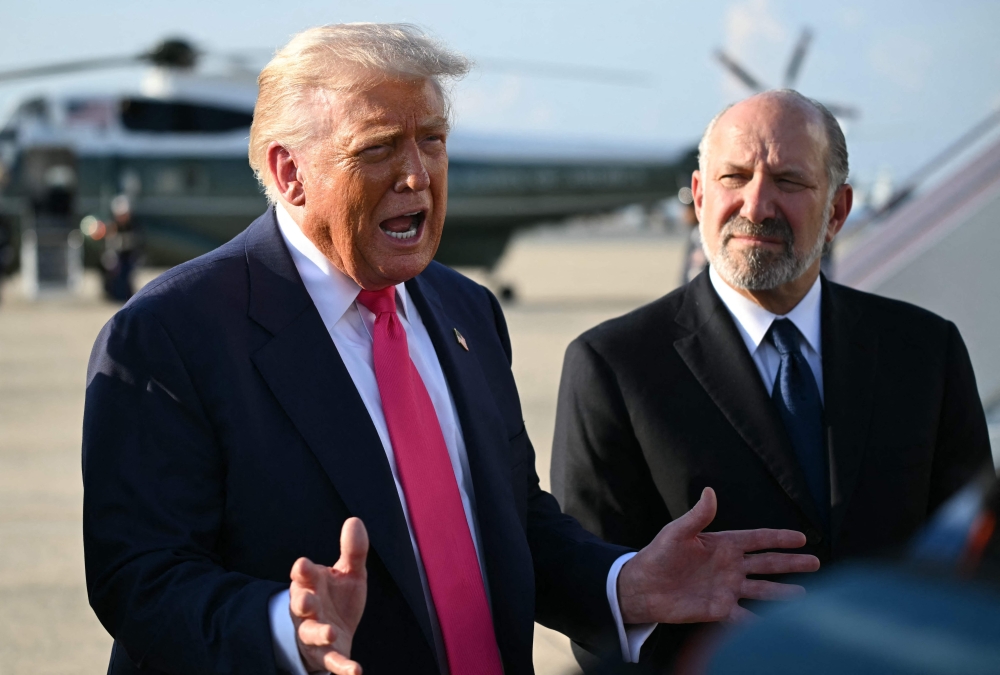 US President Donald Trump (L), flanked by US Secretary of Commerce Howard Lutnick, speaking to reporters upon arrival at Joint Base Andrews, Maryland. — AFP pic