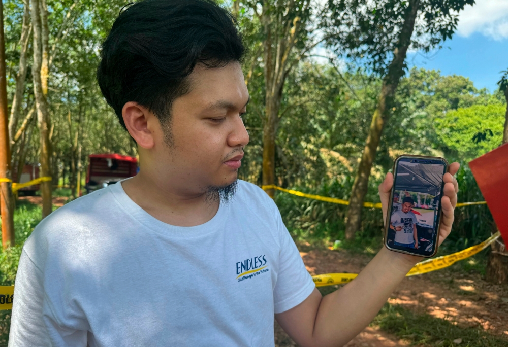 A friend of the man reported missing on Monday, Muhammad Syahmi Mansur, shows a photo of Tengku Nizaruddin Tengku Zainudin, 38, on his mobile phone in Muar, July 16, 2025. Tengku Nizaruddin was reported missing after the car he was driving plunged into Sungai Tui along Jalan Bukit Kepong. — Bernama pic 