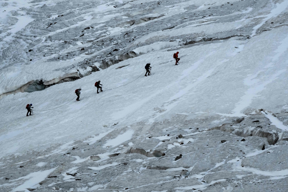 Mountaineers walk along crevasses on the Glacier de la Selle in the Ecrins Massif in Saint-Christophe-en-Oisans, early in the morning on July 9, 2025. — AFP pic