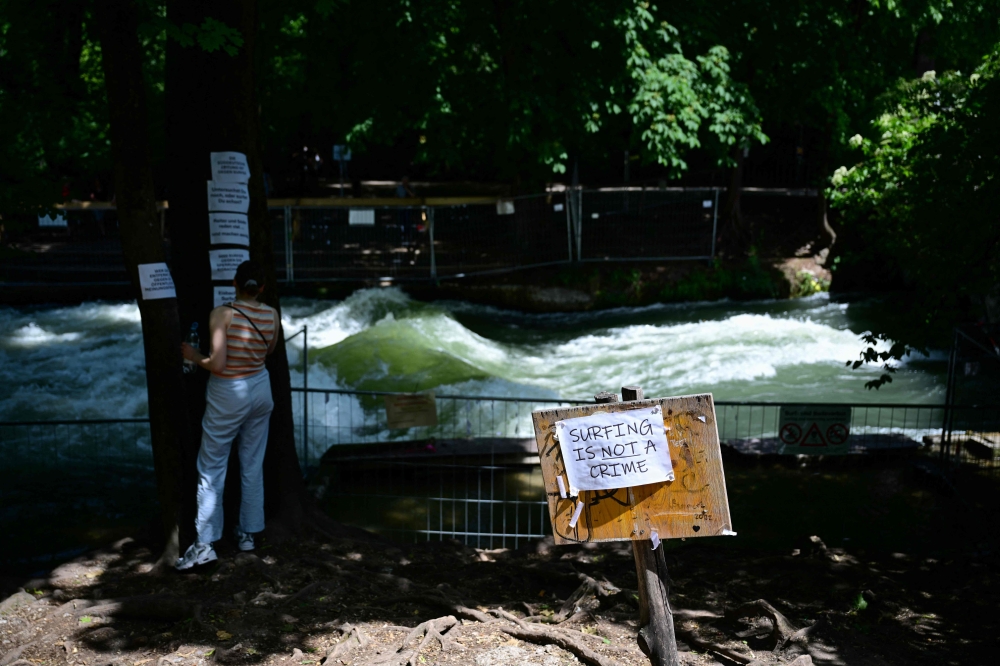 A placard reading ‘Surfing is not a crime’ in front of a fence at the Eisbach river in Munich, southern Germany, more than a month after a 33-year-old woman had an accident while surfing on the so-called Eisbach wave June 6, 2025. — AFP pic