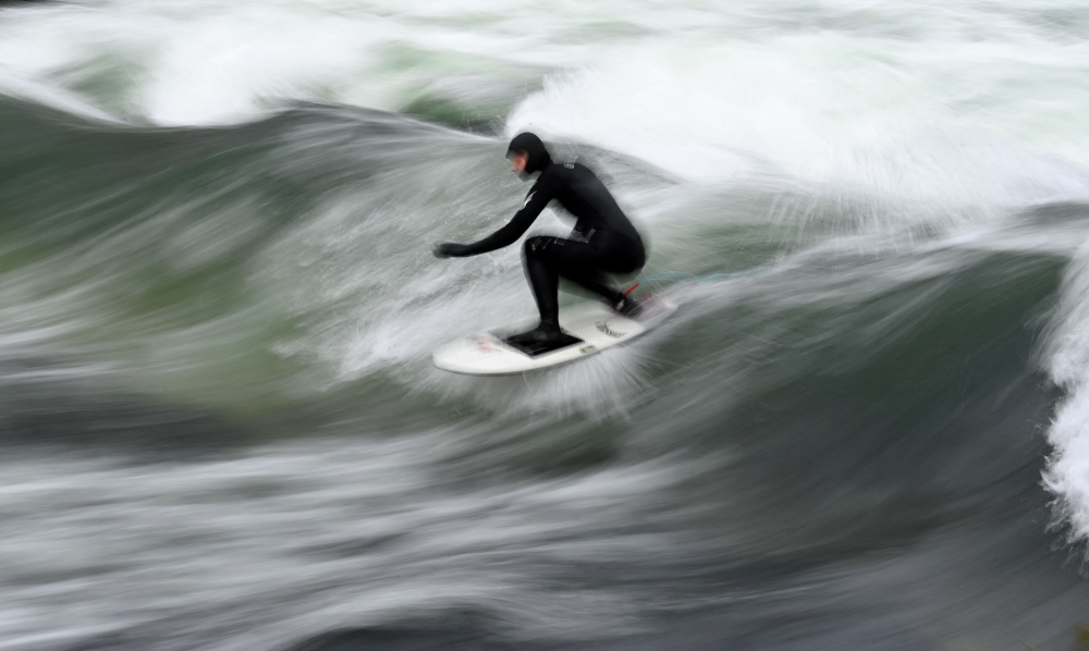 This file picture taken with long time exposure shows a surfer riding on an artificial wave in the canal of the Eisbach river at the English Garden park in Munich, southern Germany, during winter weather with temperatures by minus two degrees on January 16, 2021. — AFP pic