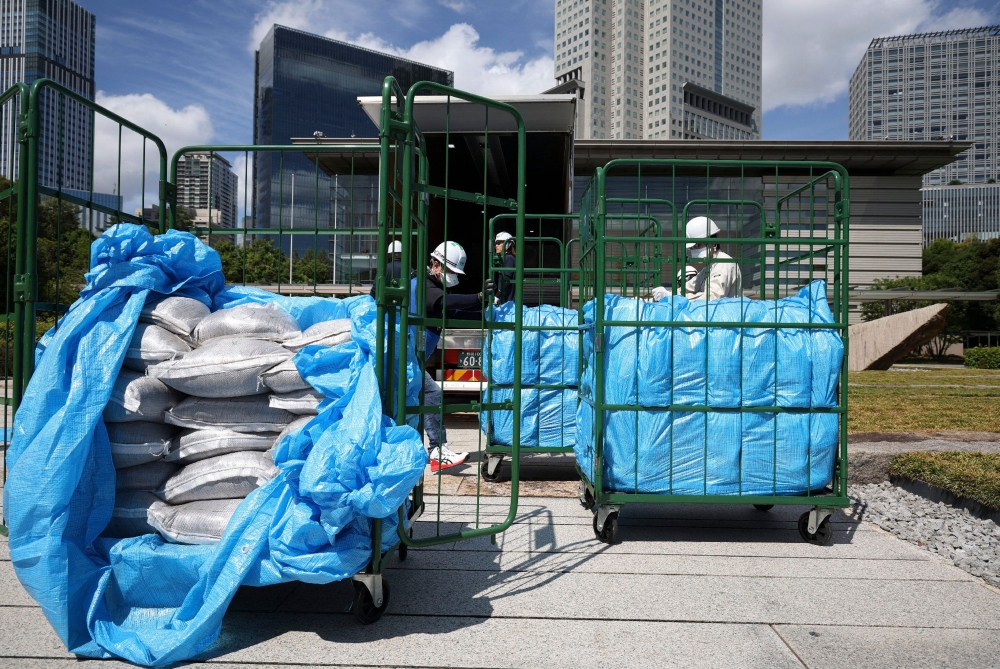 Workers unload bags of soil removed during decontamination following the Fukushima Daiichi nuclear power plant accident, at the prime minister’s office in Tokyo July 19, 2025. — AFP pic