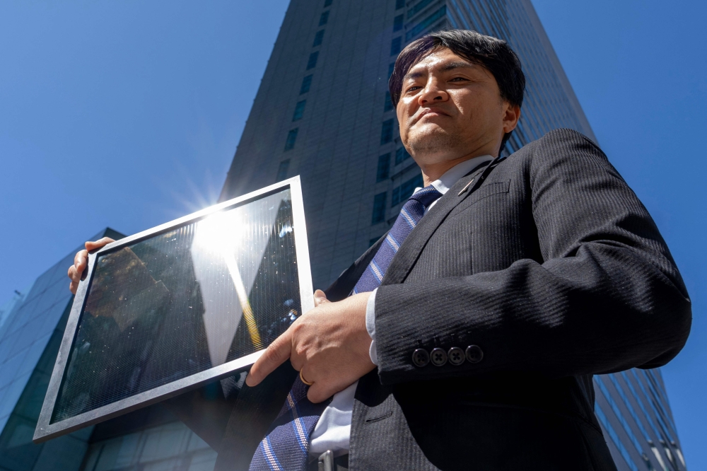 This photo taken on April 14, 2025 shows Yukihiro Kaneko, Panasonic's research officer, holding a perovskite panel. — AFP pic