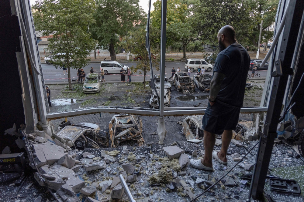 A man looks out of a broken window of a damaged building following a drone attack in Odesa yesterday. — AFP pic