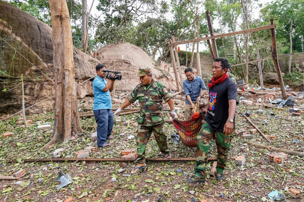 Cambodian soldiers carry the body of a victim from a pagoda damaged by Thai artillery in Oddar Meanchey province yesterday. — AFP pic