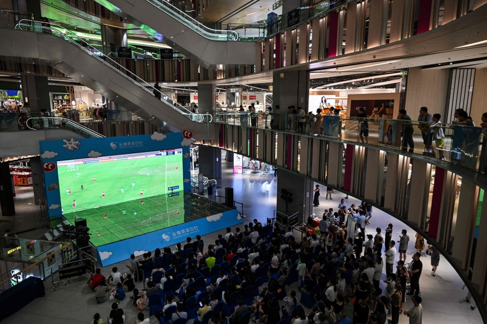 Fans look at a screen in a shopping mall showing the amateur league football match between Suzhou and Zhenjiang in Suzhou July 20, 2025. — AFP pic