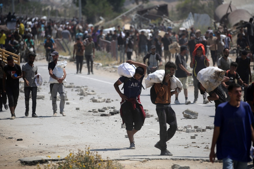 Palestinians return to the Nuseirat refugee camp with food parcels from a US-backed Gaza Humanitarian Foundation distribution point near the Netsarim corridor in the central Gaza Strip July 27, 2025. — AFP