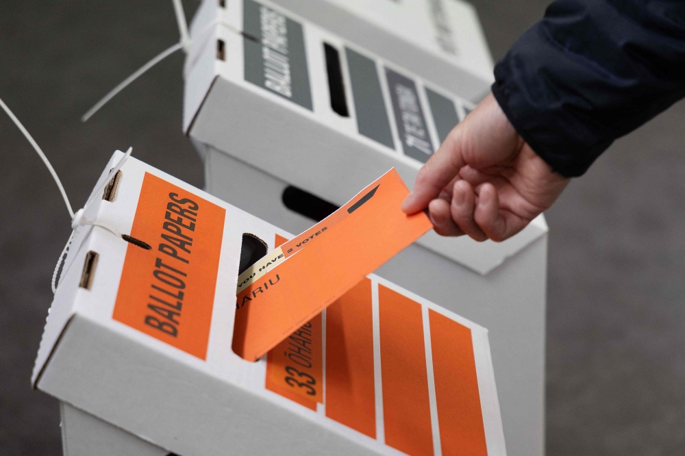 A New Zealand voter casts his vote in the 2023 general election at a voting centre at Johnsonville school in Wellington on October 14, 2023. ― AFP pic