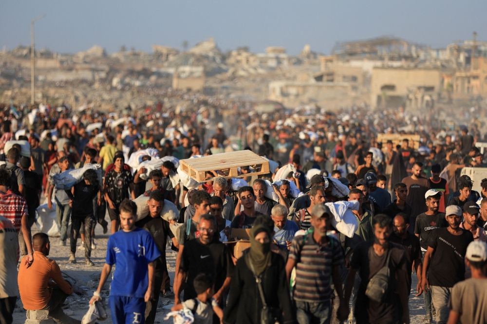 Palestinians carry aid supplies that entered Gaza through Israel, in Beit Lahia in the northern Gaza Strip, July 30, 2025. Gaza’s civil defence agency said Israeli forces killed at least 30 people when they opened fire Wednesday on a crowd waiting for humanitarian aid in the north of the Palestinian territory. — Reuters pic 