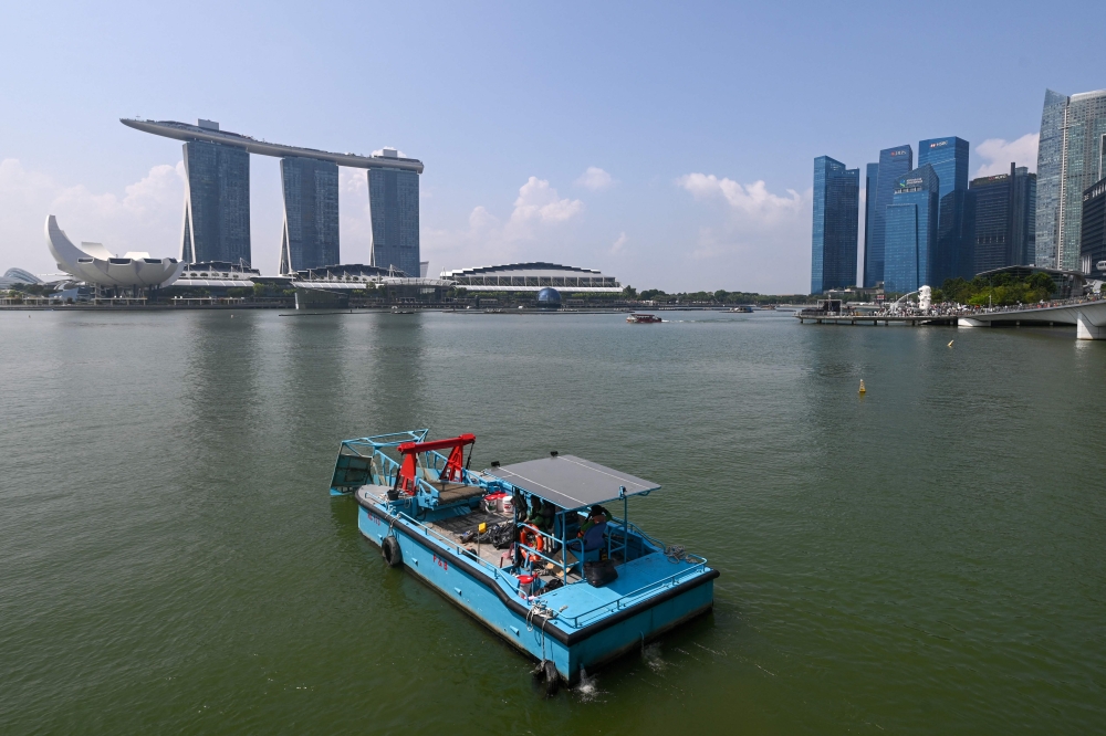 Workers on a barge clear rubbish from the water of Marina Bay in Singapore on July 30, 2025. The services sector in Singapore expects business conditions to improve and become more favourable in the second half of the year, according to the Singapore Department of Statistics’ (DOS) Business Expectations Survey for the sector. — AFP pic 