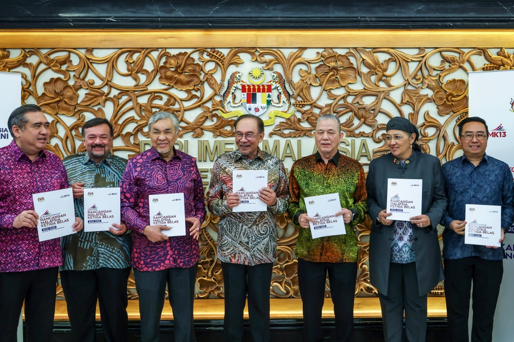Prime Minister Datuk Seri Anwar Ibrahim holds up the 13th Malaysia Plan (13MP) booklet after tabling it in the Dewan Rakyat in Kuala Lumpur July 31, 2025. — Bernama pic