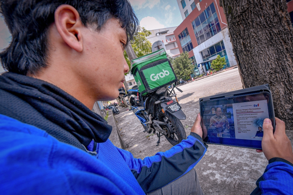Food delivery man Afif Hakim Sulaiman 22, watches the live broadcast of the 13th Malaysia Plan presented by Prime Minister Datuk Seri Anwar Ibrahim while waiting for his food order during a survey in Section 14 Shah Alam July 31, 2025. — Bernama pic