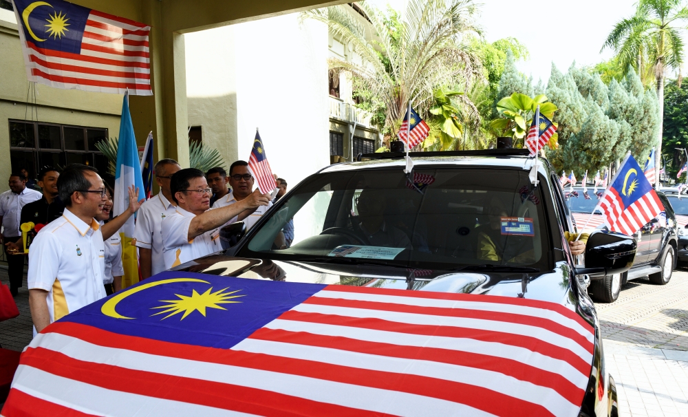 Penang Chief Minister Chow Kon Yeow (2nd left) affixes the Jalur Gemilang to a vehicle while sending off the Jalur Gemilang convoy at the launch of the Penang-level National Month and Flying the Jalur Gemilang celebration in George Town August 1, 2025. — Bernama pic
