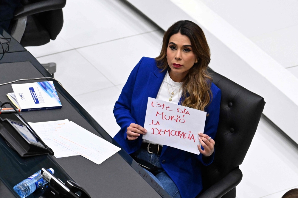 Opposition Arena Deputy Marcela Villatoro holds a sign that reads ‘Democracy died today’ during a Congress plenary session in San Salvador July 31, 2025. — AFP pic