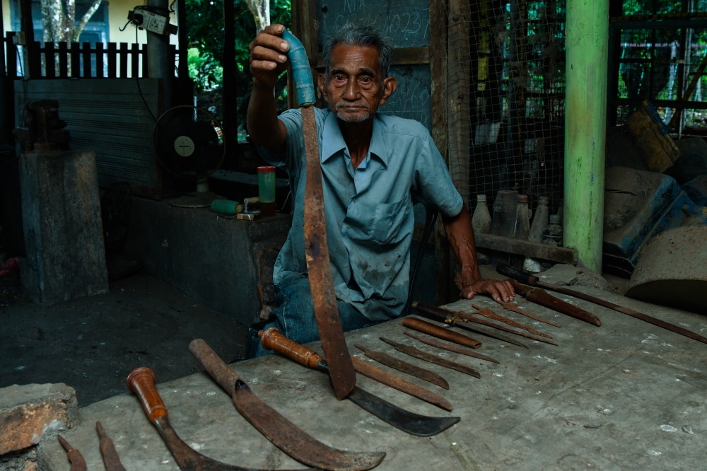 Fauzi Yusoff shows some of the machetes, sickles, knives and keris he has made at his workshop in Kampung Hutan Pasir, Ketereh. — Bernama pic
