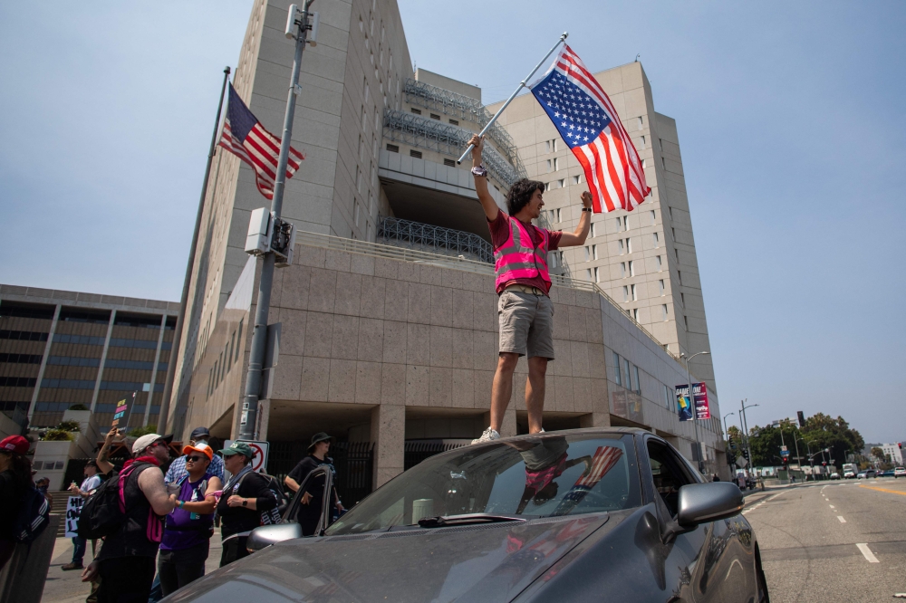 A man holds an upside down American flag as part of the peaceful protest Rage Against the Regime against US President Donald Trump Administration’s raids on communities, immigration, LGBTQIA  people, due process, and democracy in front the Edward R. Roybal Federal building and Detention Center on on August 2, 2025 in Los Angeles, California. — AFP pic