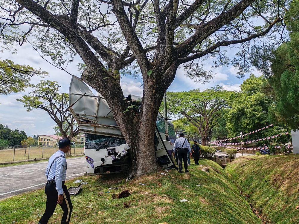 Police at the scene where a school bus carrying kindergarten pupils crashed into a tree in Serdang. — Picture courtesy of PDRM