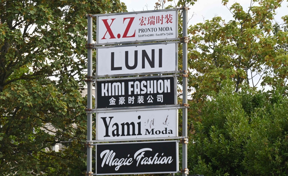 This photograph show advertising signs for fast-fashion outlet factories in the industrial district of Prato, central Italy, on August 1, 2025. — AFP pic