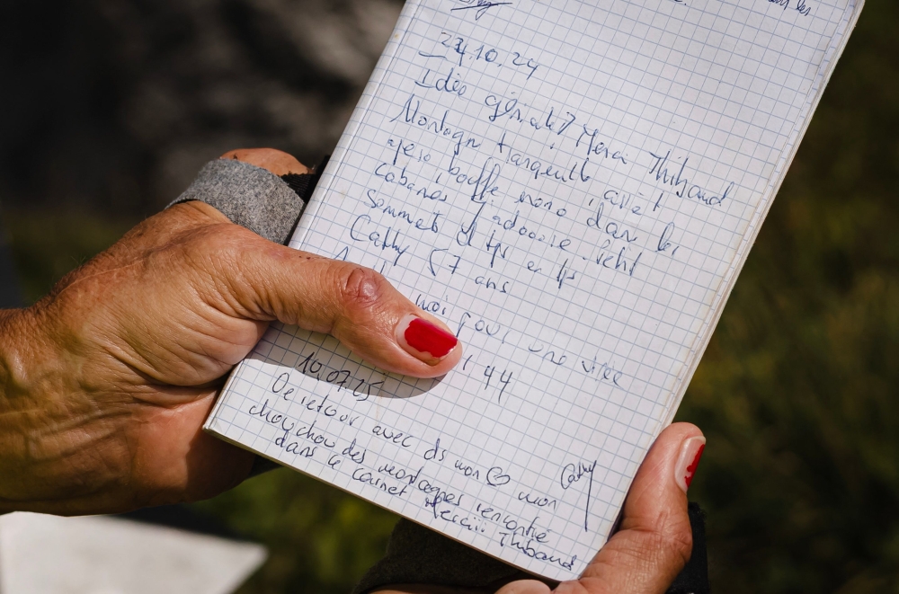 Cathy, 58 years old, reads the ‘Mountain Tinder’ notebook at the top of Wandflue peak, Bernese Alps, above Jaun of the Canton of Fribourg, on August 3, 2025. — AFP pic 