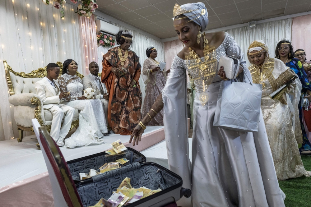 Amadi Maria (4th left), the mother of Franco Comoran Faid Kassim (3rd left), who lives with his wife Faizat Aboubacar (2nd left) in Reunion, stands next to the couple as friends and relatives drop banknotes in a suitcase while dancing during the Ukumbi, a women only reception marking the end of the Grand Mariage celebrations, at the Foyer des Femmes (a local venue dedicated to women only gathering) in Moroni, on July 20, 2025 during the evening reception of the couple's Grand Mariage. Gold and other gifts are brought by the groom to the bride as a dote in an elaborate ceremony in which the whole extended families and members of the community take part. — AFP pic 