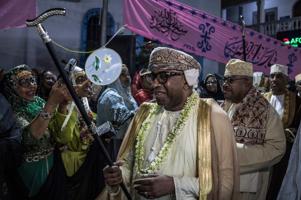 Issa Mze Ali Ahmed (centre), a Franco Comorian who travelled back to Comoros to celebrate the Grand Mariage swings his stick as he joins the traditional Dinahou dance on the central Badjanani square in Moroni on July 19, 2025 during the Madjiliss ceremony. Madjiliss is a traditional ceremony in which religious chanting and rhythmic dancing introduce the groom during the Grand Marriage celebrations. — AFP pic