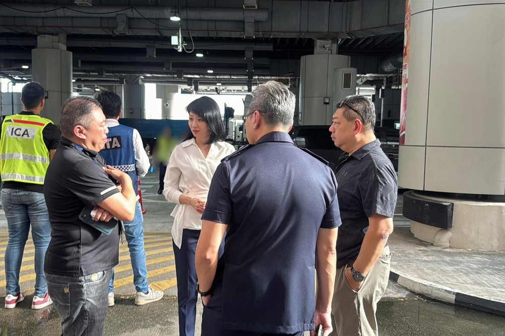​​Senior Minister of State for Transport Sun Xueling (in white top) speaks with ICA and LTA officers at Woodlands Checkpoint. — Picture from Facebook/Sun Xueling