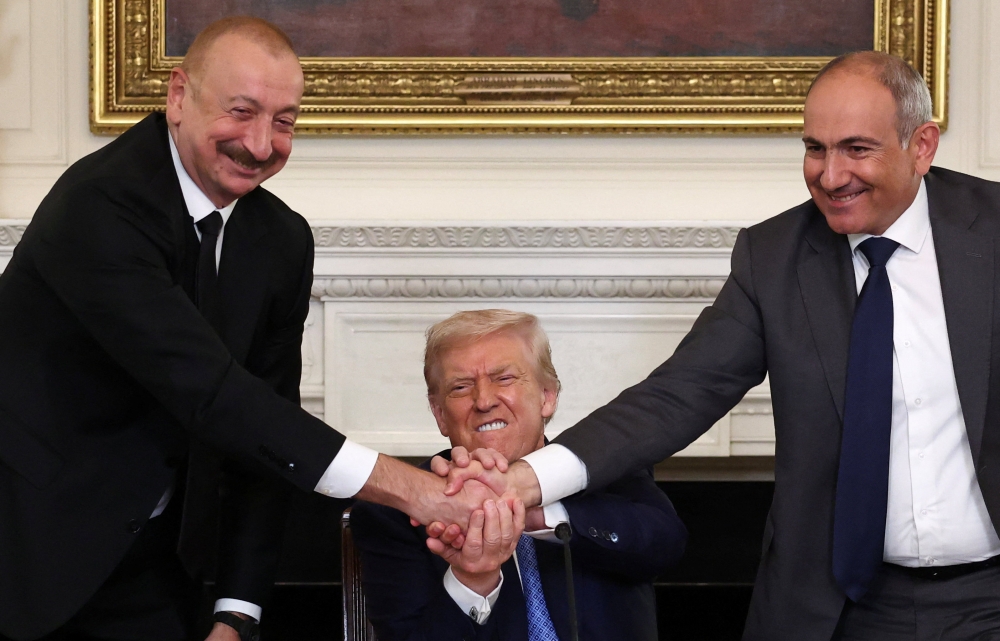 US President Donald Trump holds the hands of Azerbaijan’s President Ilham Aliyev and Armenia’s Prime Minister Nikol Pashinyan as they shake hands between each other during a trilateral signing event, at the White House, in Washington August 8, 2025. — Reuters pic
