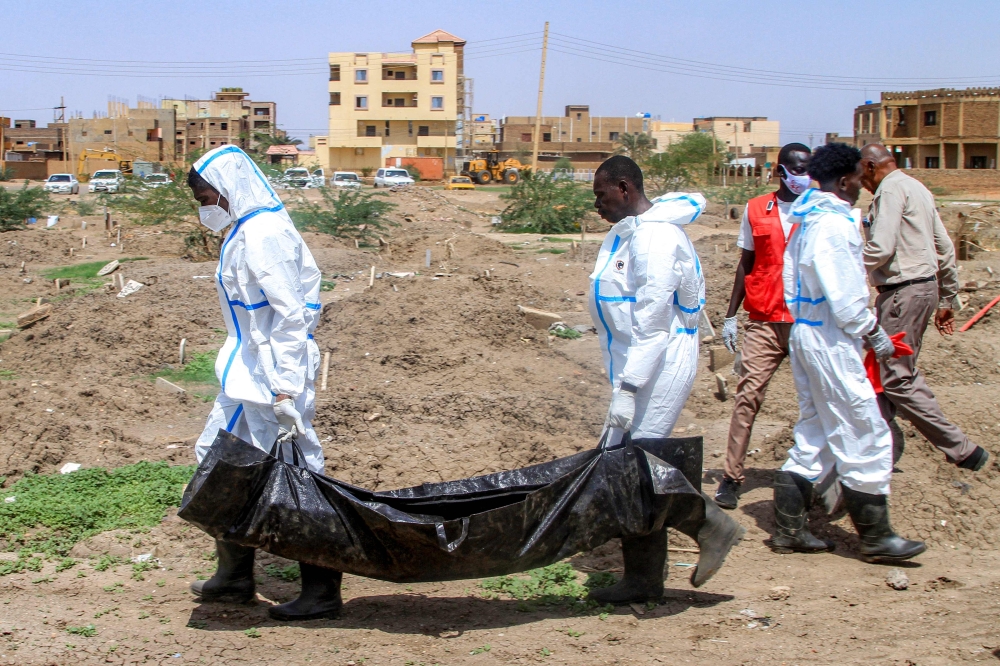 Members of the Sudanese Red Crescent carry in a bag the exhumed remains of a person from a makeshift grave for reburial in the local cemetery in Khartoum's southern suburb of al-Azhari on August 2, 2025 after the dead were buried in a rush when the area was under control of the Rapid Support Forces (RSF) paramilitaries. — AFP pic