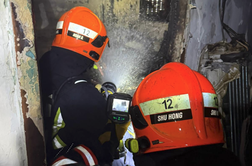 Firefighters damp down the affected unit after putting out the fire. — Singapore Civil Defence Force pic