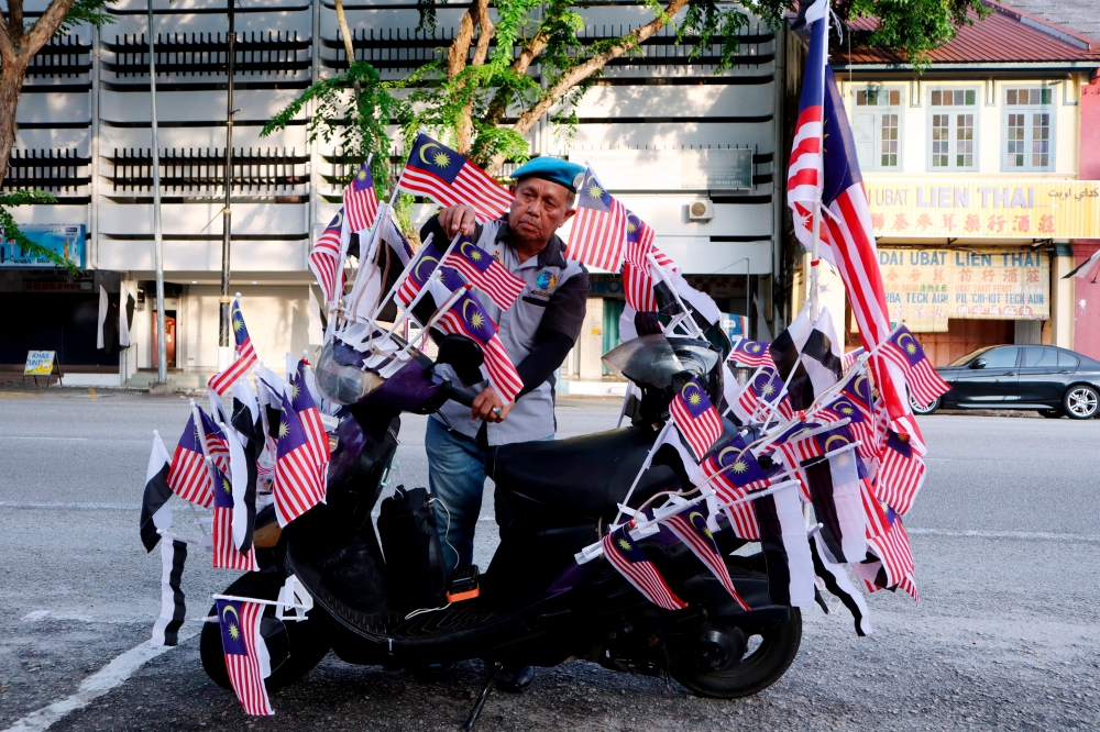Retired soldier Mohd Mustafa, 64, proudly decorates his scooter with the Jalur Gemilang. — Bernama pic