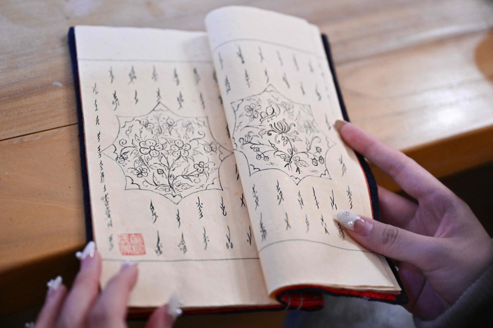 This picture taken on April 14, 2025 shows a student holding a book with ‘Nushu’ characters during a workshop in Beijing. — AFP pic 