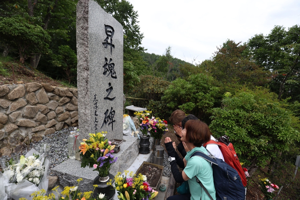 Bereaved family of victims of the Japan Airlines Flight 123 crash, the world's deadliest single-aircraft accident with 520 killed, pray in front of the memorial altar at the crash site on Mount Osutaka in Ueno Village, Gunma Prefecture on August 12, 2025. — AFP