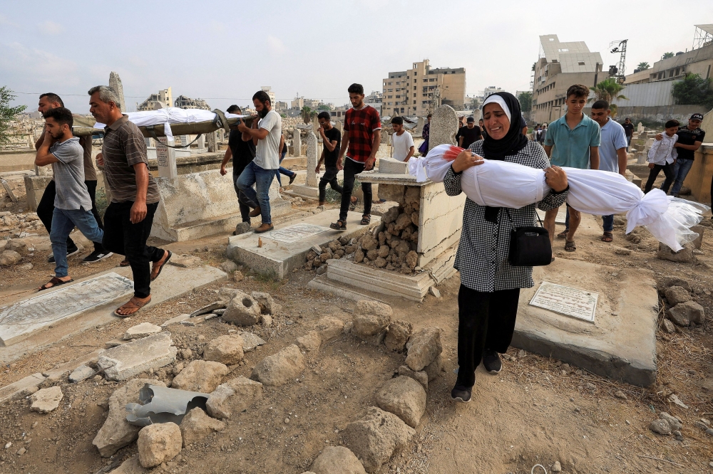 Palestinian woman Soha Tafesh carries the body of her granddaughter Sarah Abu Daf, who was killed in an early morning Israeli strike on a house, according to medics, at a cemetry in Gaza City, August 13, 2025. — Reuters pic 