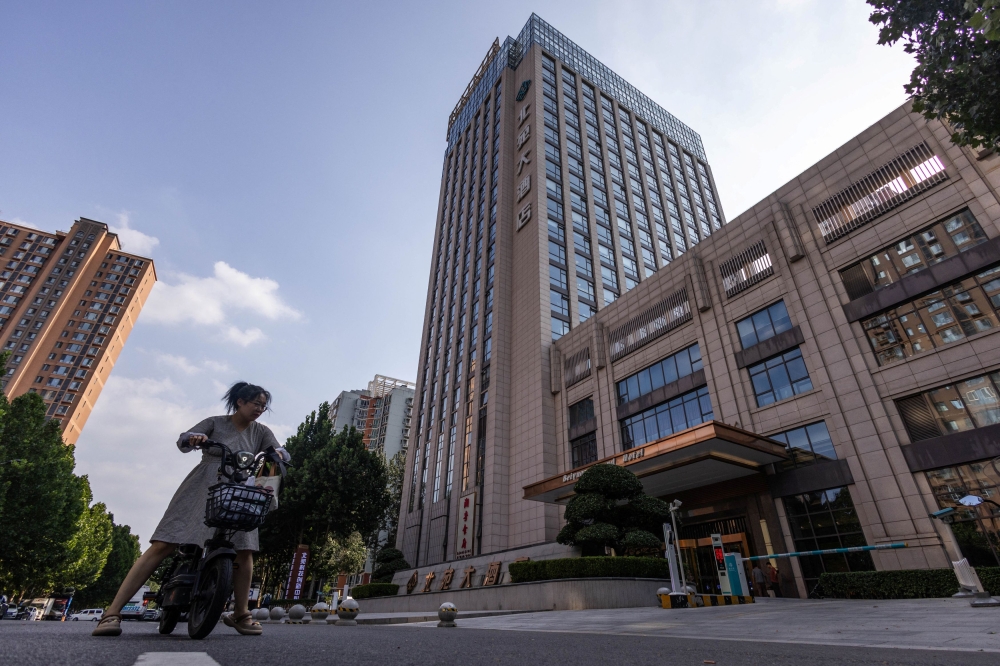 A woman rides an electric scooter by the Beiyuan Grand Hotel in Beijing August 11, 2025. — Reuters pic  