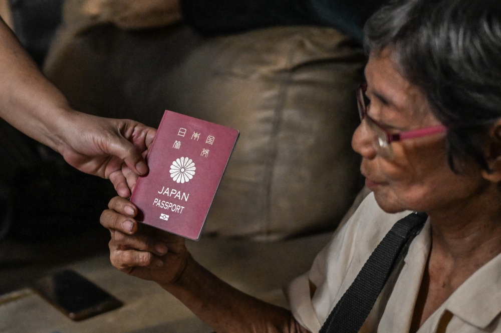Maria Corazon Nagai shows her Japanese passport. — AFP pic