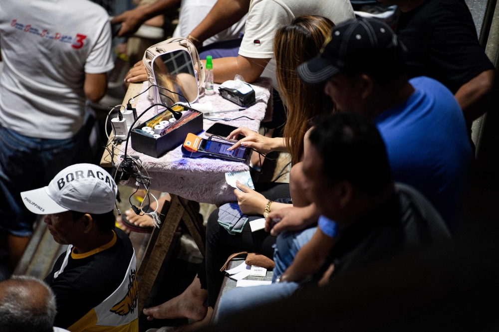 An employee of a cockfighting arena operates a wager machine in Bulacan province, north of Manila, July 5, 2025. — AFP pic