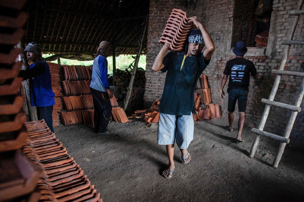 Roof tile factory workers handling tiles before taking part in a traditional bodybuilding competition at a roof tile factory in Jatiwangi, West Java, August 11, 2025. — AFP pic