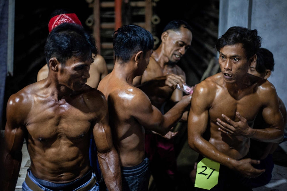 Roof tile factory workers smear each other’s bodies with oil before taking part in a traditional bodybuilding competition at a roof tile factory in Jatiwangi, West Java, August 11, 2025. — AFP pic