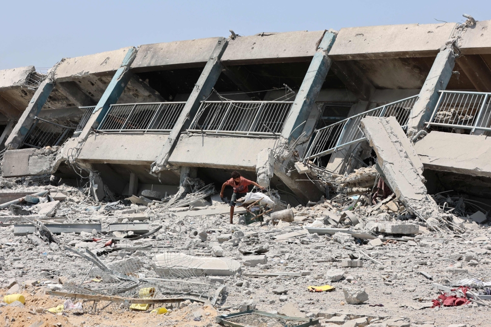 A Palestinian boy collects wood, to salvage to be used as firewood, next to a destroyed building in the al-Tuffah neighbourhood of Gaza City on August 14, 2025, following more than 22 months of war between Israel and the Palestinian group Hamas. — AFP pic