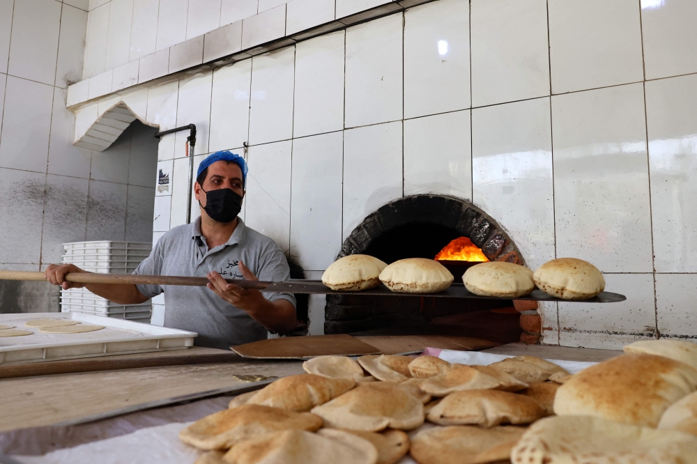 An Egyptian baker works in front of an oven at a bakery in Riyadh on August 14, 2025, during the soaring summer heat.  — AFP pic