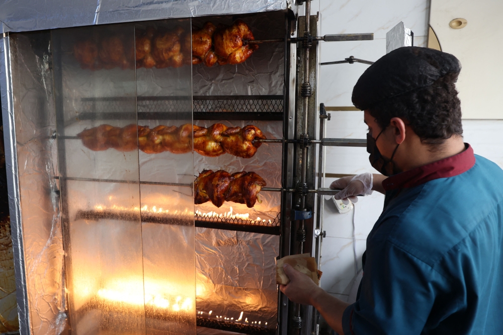 Yemeni Hani Al-Duaisi, 26, works in front of a chicken griller at a shop in Riyadh on August 13, 2025, during the soaring summer heat. — AFP pic
