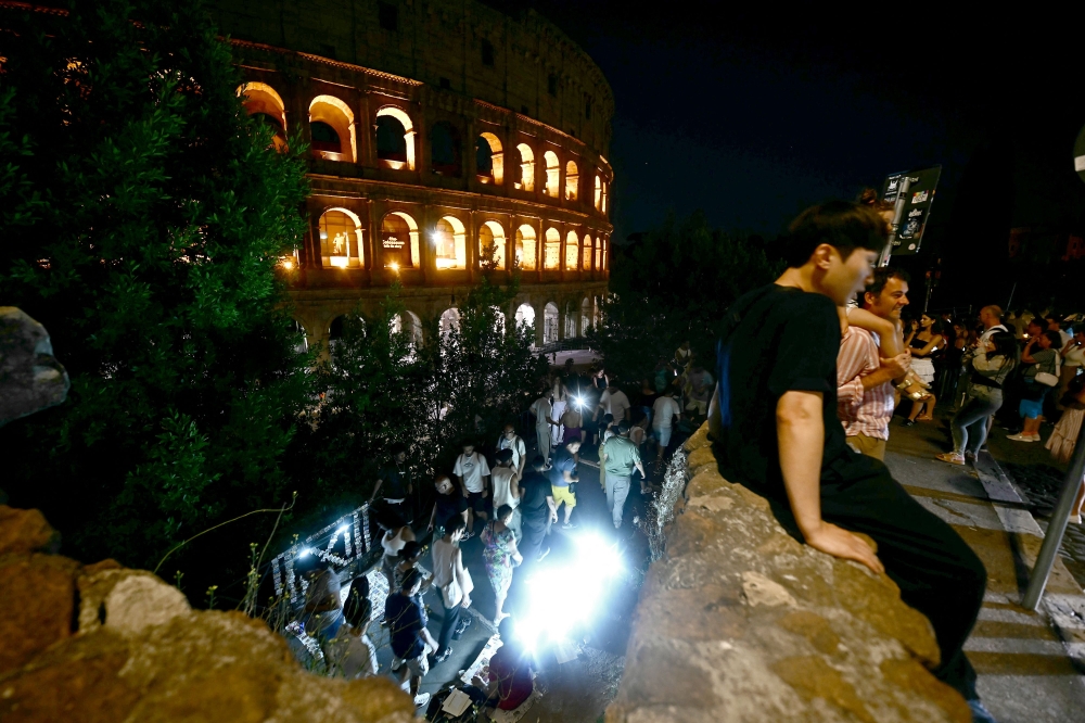 People sit in front of the Colosseum in central Rome August 13, 2025. — AFP pic