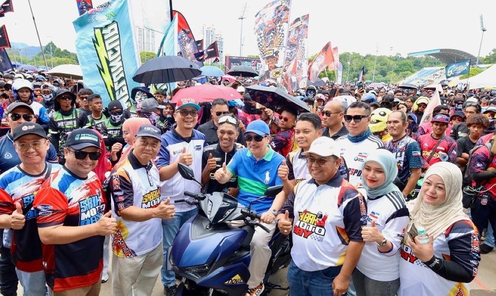 Chief Minister Datuk Seri Panglima Haji Hajiji Haji Noor poses with the Sabah Moto Day participants while sitting on a motorcycle. — The Borneo Post pic