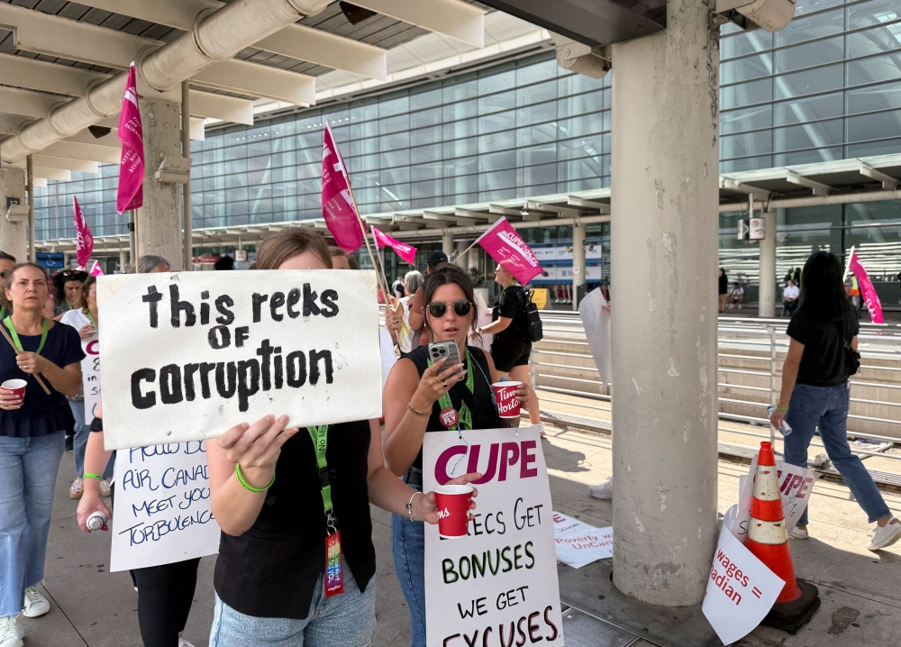 A demonstrator holds a placard at Toronto Pearson International Airport in Mississauga, Ontario, on August 17, 2025.  — Reuters pic