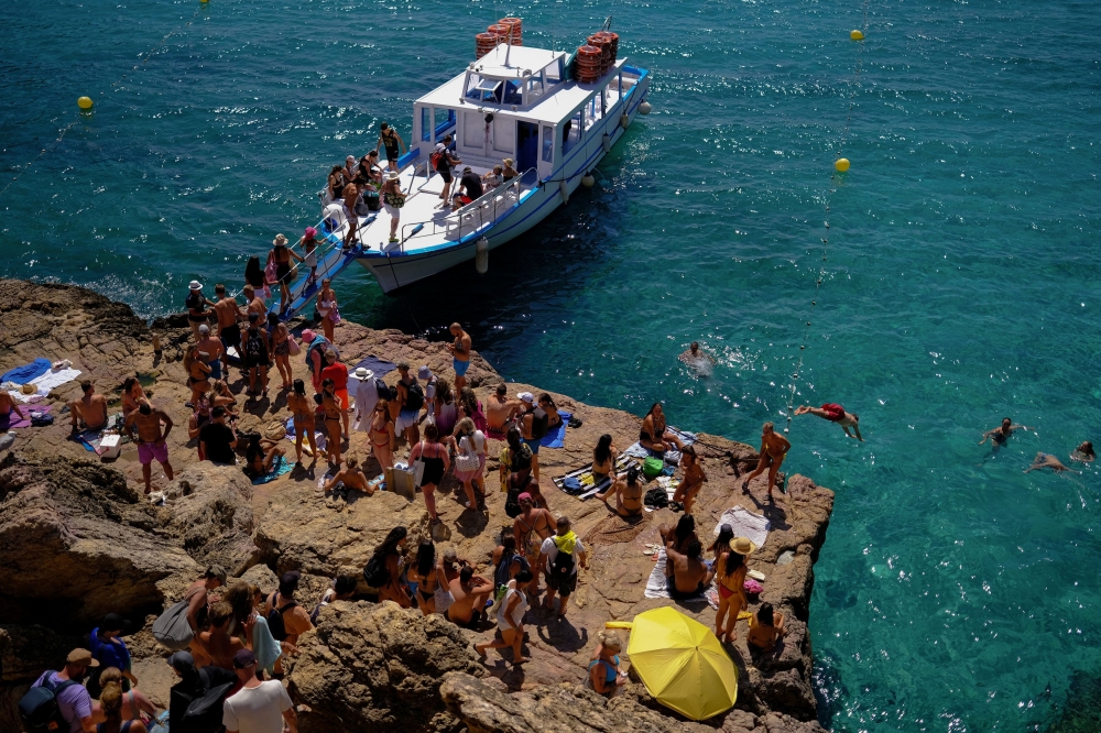 Tourists enjoy the sea as others board a beach touring boat at Cala Saladeta beach in Sant Antoni de Portmany, Ibiza, Spain, July 26, 2025. — Reuters pic