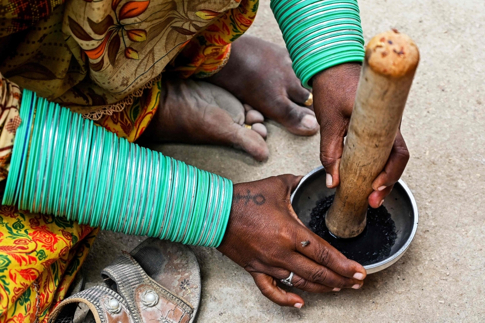 This photograph taken on July 14, 2025 shows artist Guddi Manthar, grinding charcoal with goat milk using a traditional pot, before drawing indigenous tattoos at the Jogi Colony in Umerkot, a Hindu-majority district in Pakistan. — AFP pic 