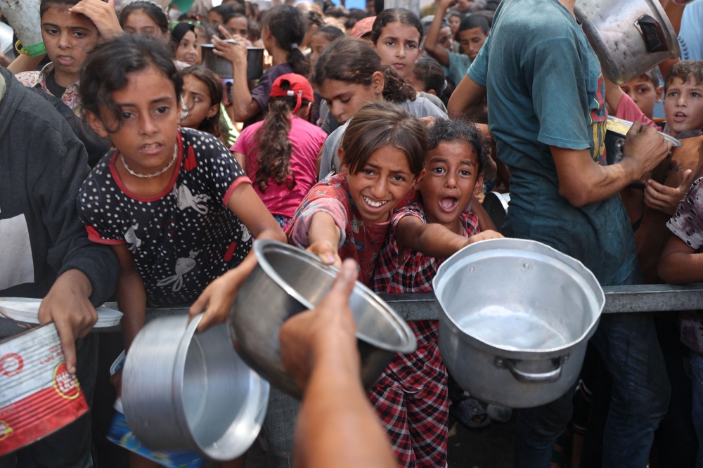 Palestinians gather to receive cooked meals from a food distribution center in the Nuseirat refugee camp in the central Gaza Strip on August 18, 2025. — AFP pic 