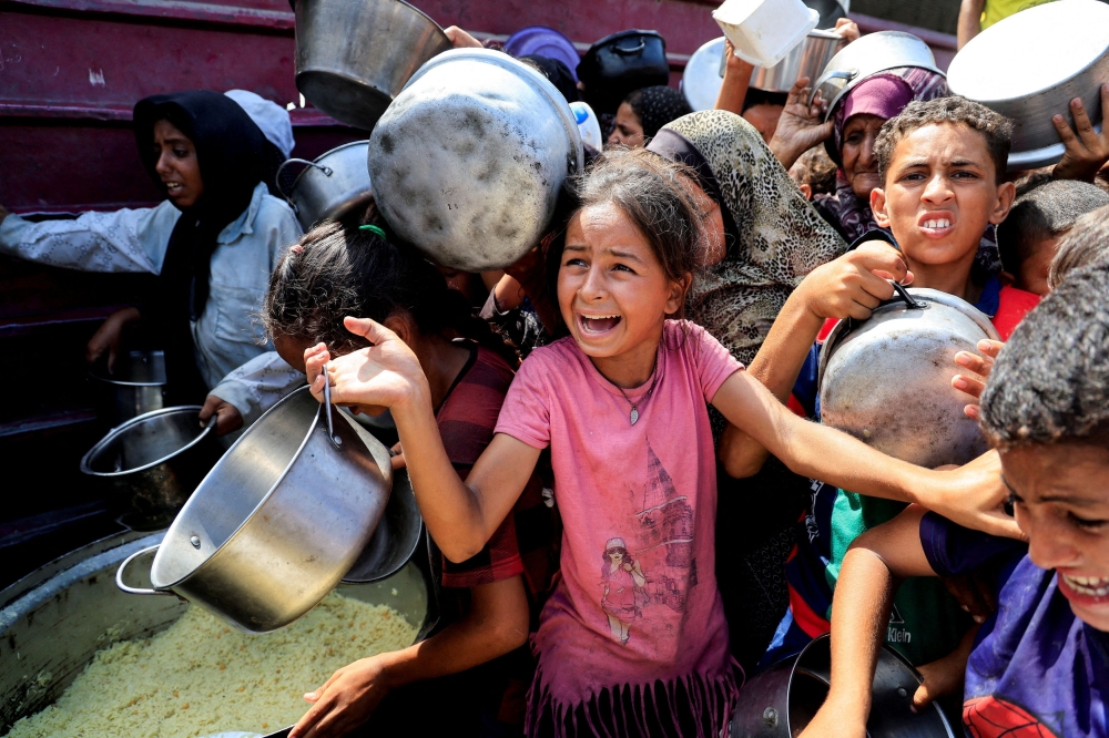 Palestinians wait to receive food from a charity kitchen, in Khan Younis, southern Gaza Strip, August 21, 2025. — Reuters pic