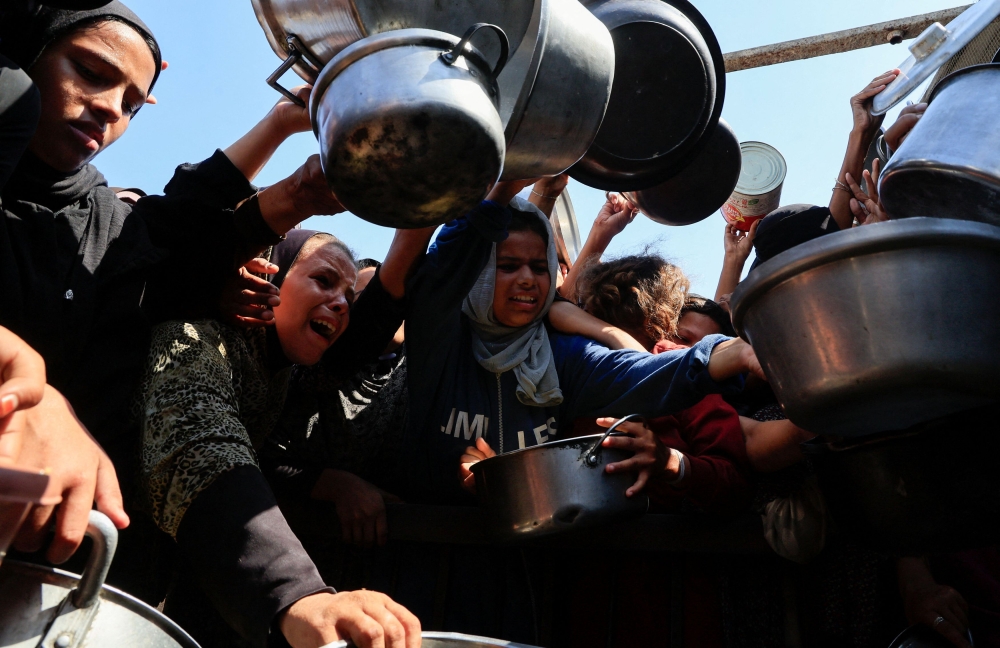 Palestinians hold pots while waiting to receive food from a charity kitchen in Khan Younis, southern Gaza Strip, August 21, 2025. — Reuters pic